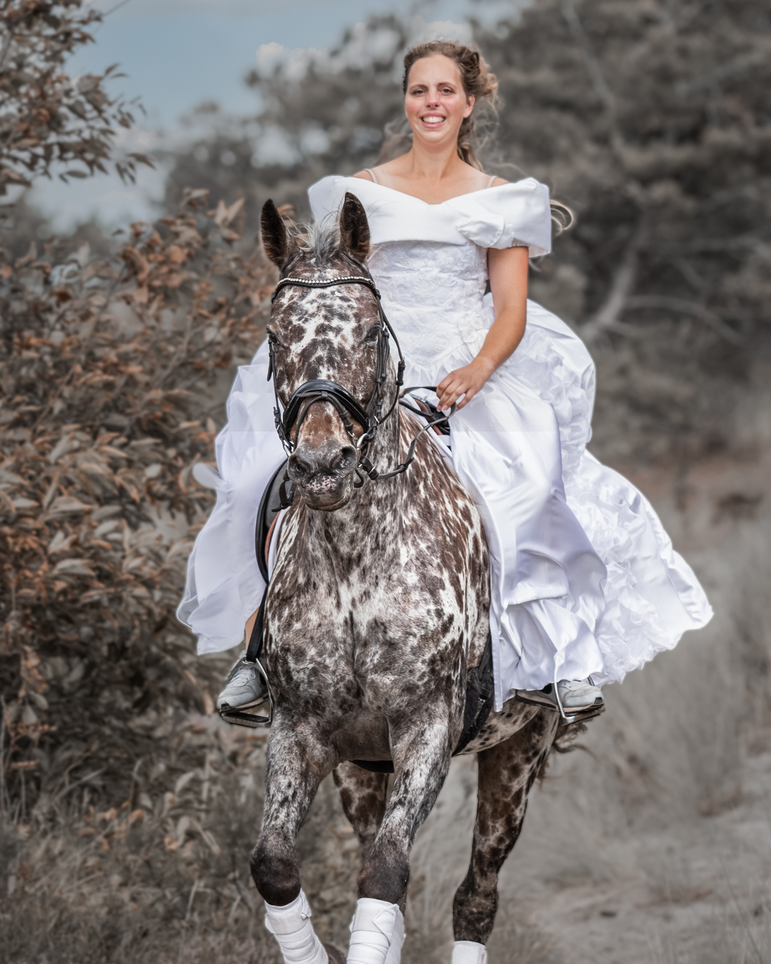 Bruid rijdend op haar paard in een trouwjurk in de duinen van Hargen aan Zee.
