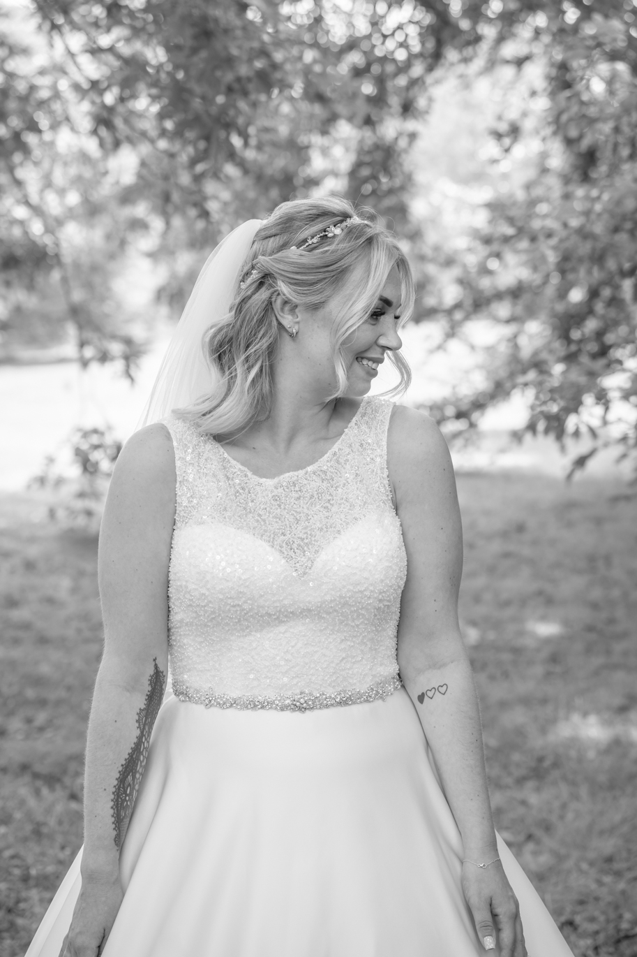 bruid kijkt over haar schouder. Heeft een witte trouwjurk aan en de foto is gemaakt in zwart wit.