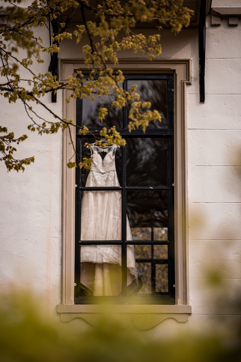 Trouwjurk door het raam van het landgoed op de Veluwe. Mooie groene uitstraling en romantisch.